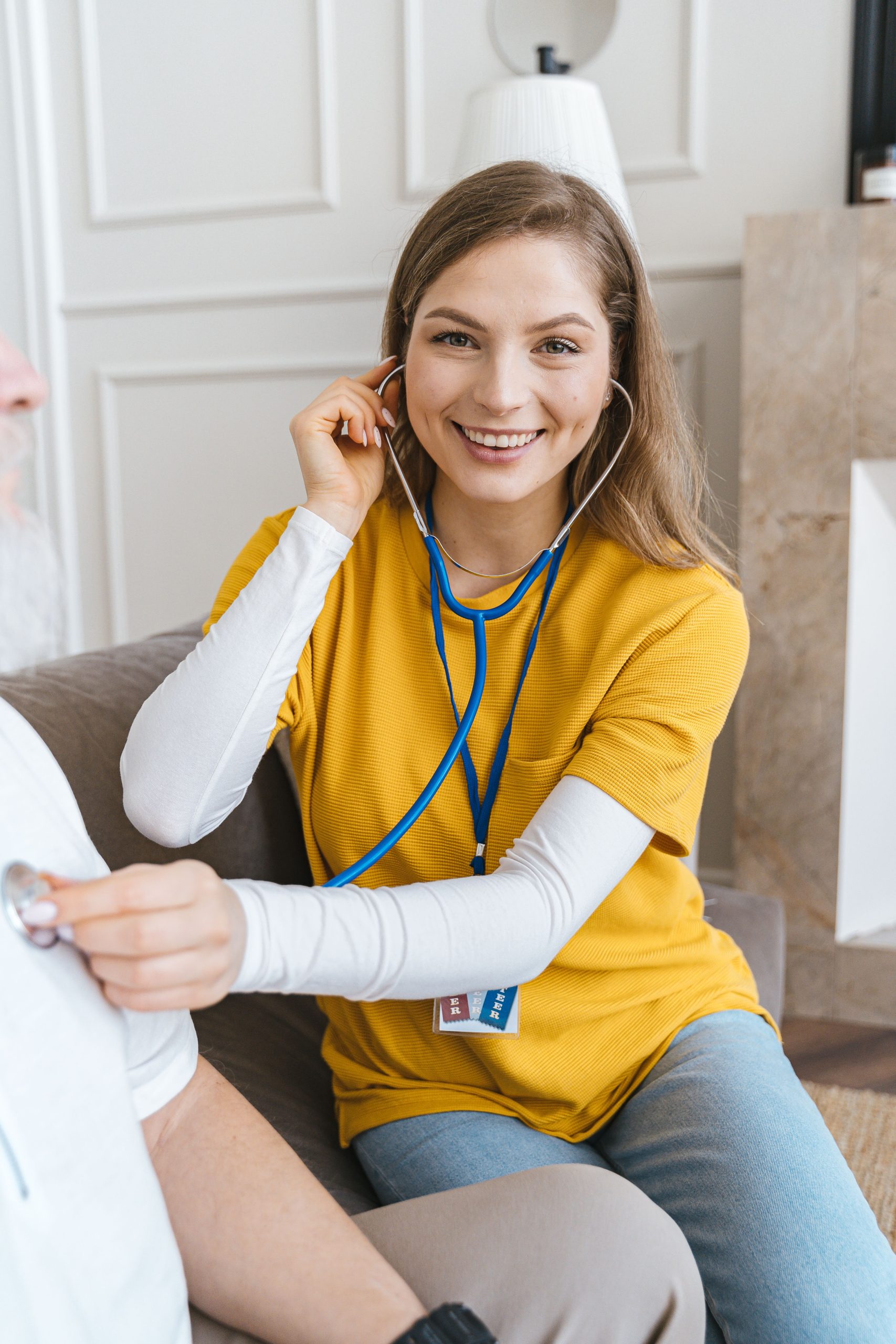 Home health clinician using a stethoscope during an in-home patient visit